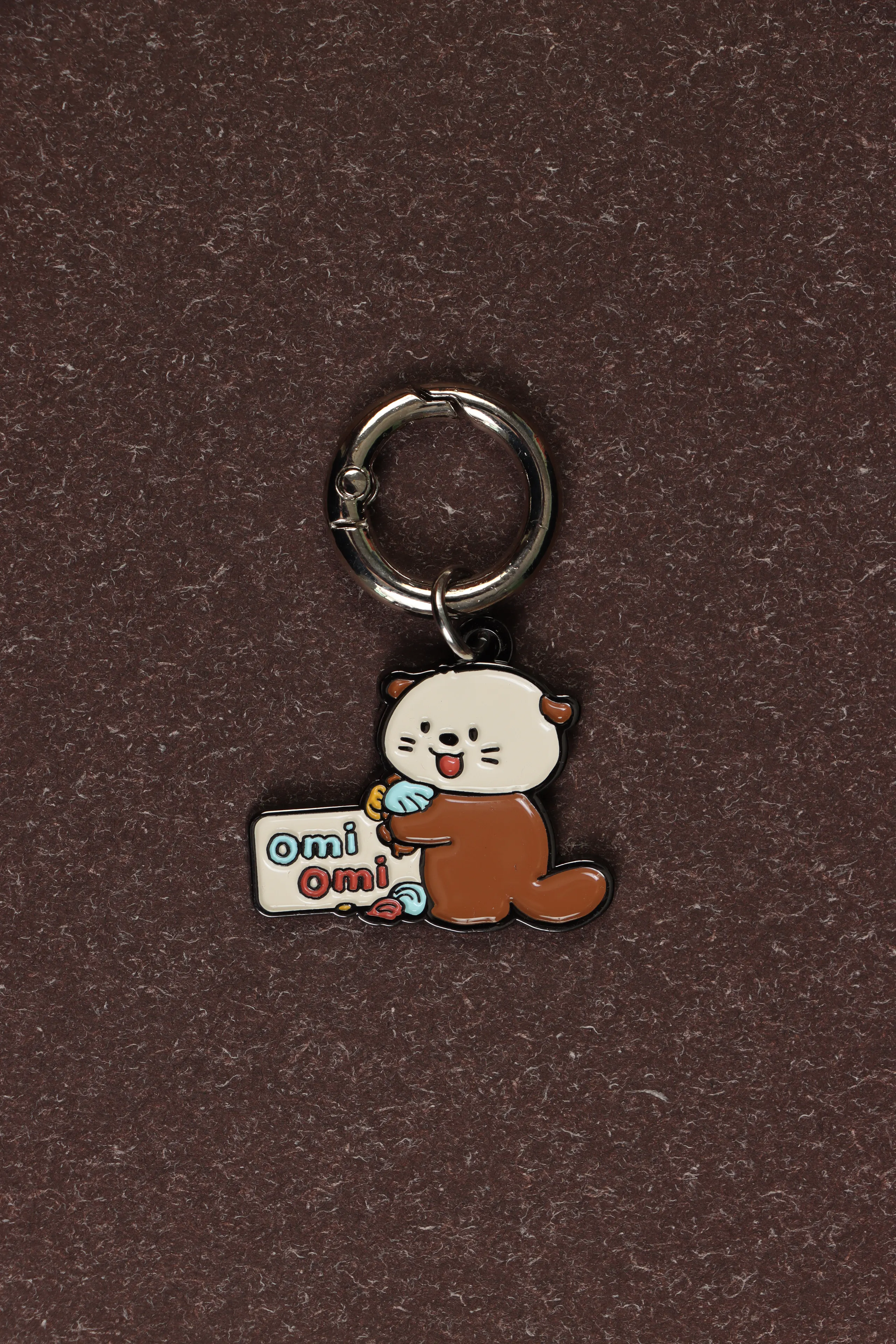 An OMIOMI keychain photographed on a cocoa surface
